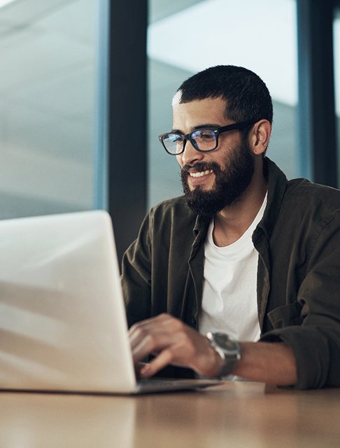 Man smiling while working on laptop at office