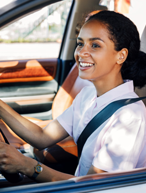 Woman in white shirt smiling while driving