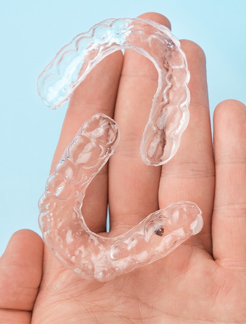 Two Spark clear aligners sitting in open palm